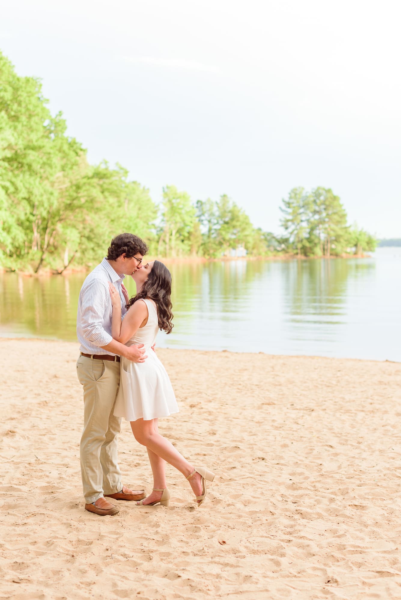 The bride and groom kiss during their engagement photos with the Jetton Park beach in the background.